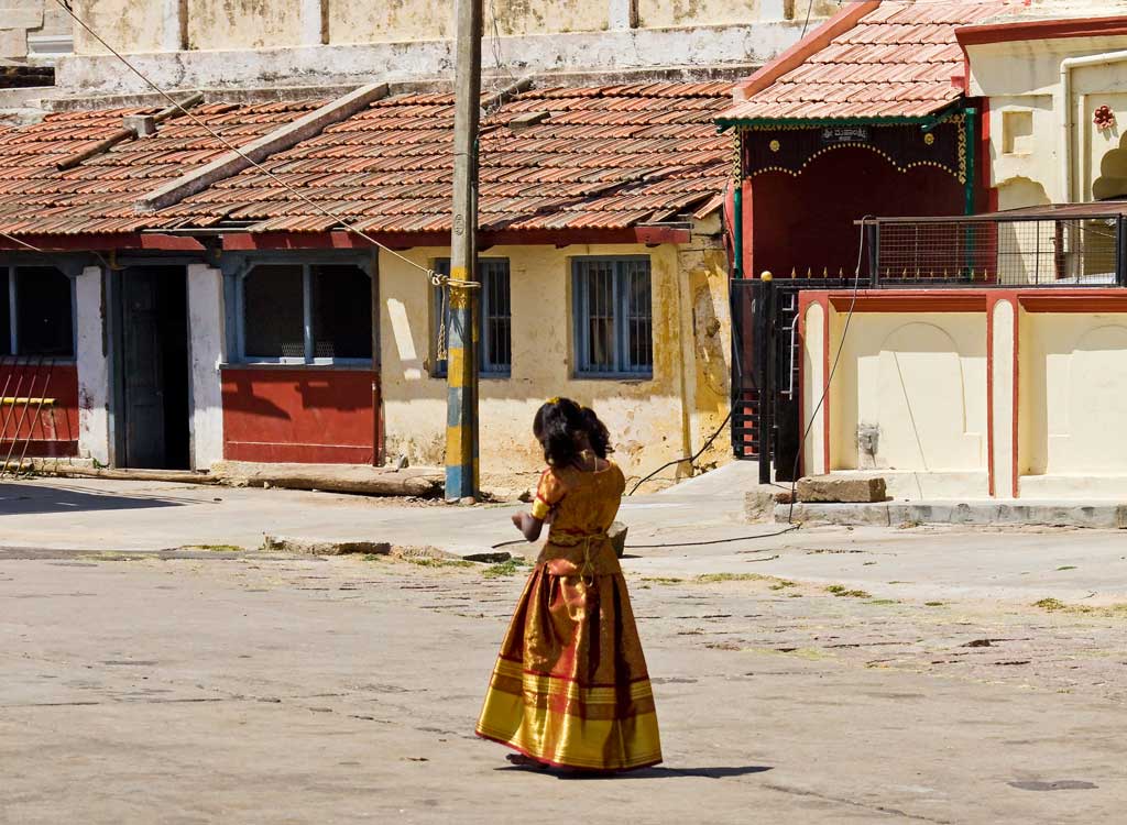 A young girl dressed in red and gold outside of Chamundeshwari temple on top of Chamundi Hills in India