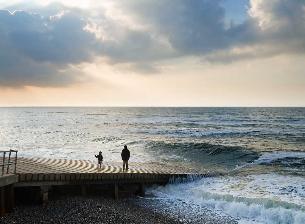 Man and child running from the waves in Sherringham, Norfolk